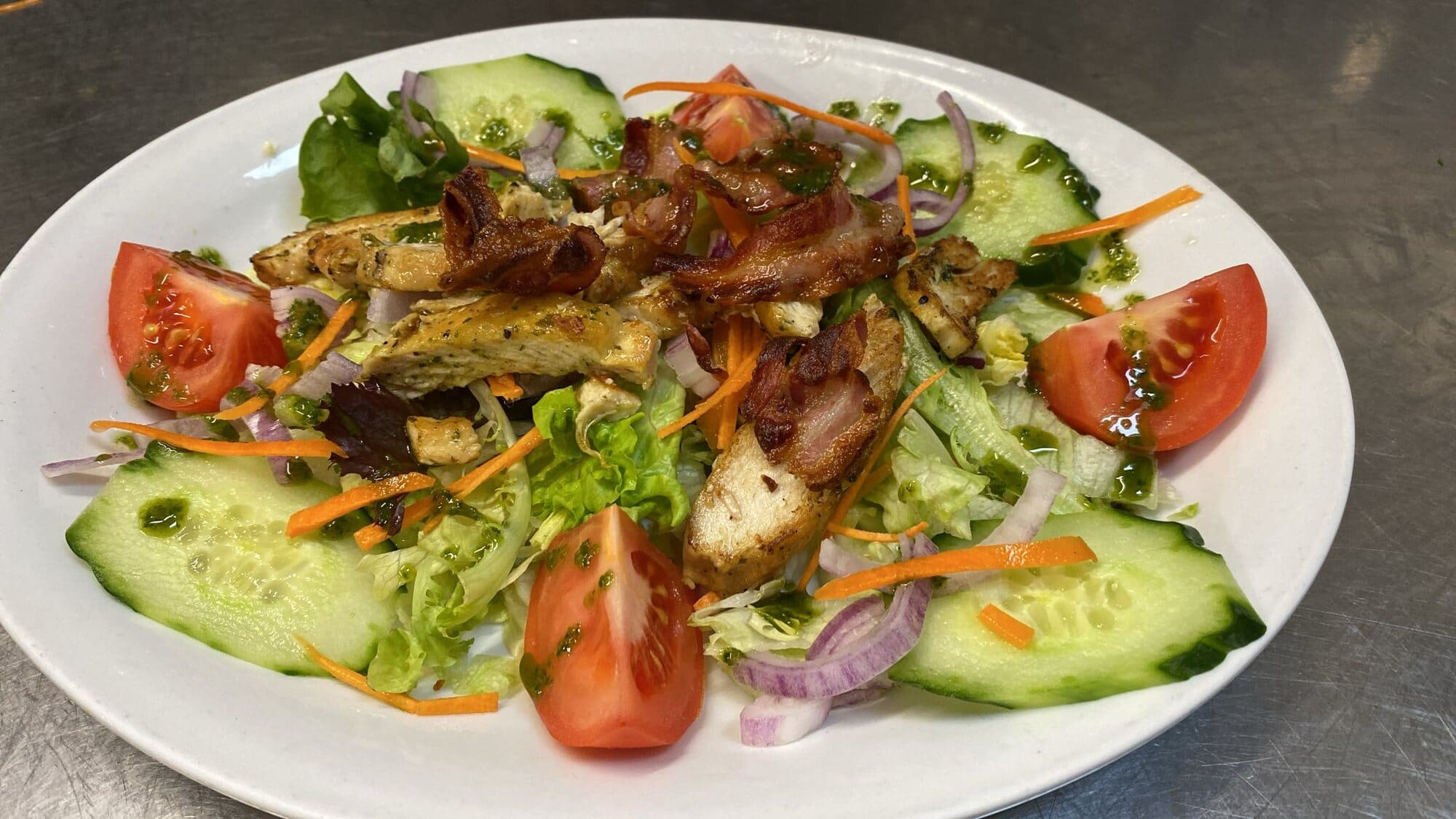 Salad of mixed leaves, tomato, cucumber, red onion and carrot topped with grilled chicken and crispy bacon at Fabio's in Swindon
