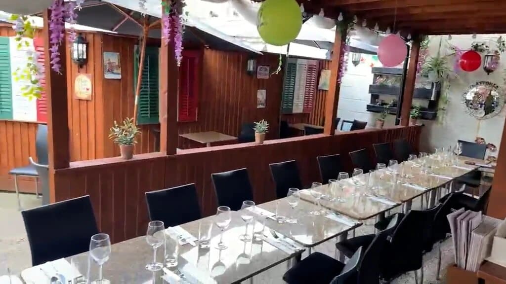 A long table set with glasses under the pergola in Fabio's outside dining area, with Italian-style shutters behind